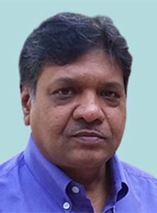 A man in a blue shirt is standing in front of a blue background.