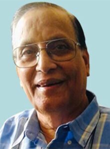 An older man wearing glasses and a blue shirt.