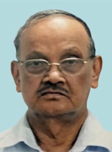An indian man wearing glasses and a blue shirt.
